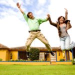 couple jumping in front of house